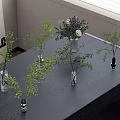 Glass Vases with Green Foliage and White Flowers Decorative Arrangement on Wooden Table with Natural Light