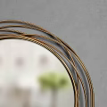 Round Gold Framed Mirror With Multiple Layers Of Lines On Gray Background