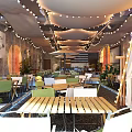 Cozy Casual Lounge Area With String Lights Umbrella Gray Walls Plants And Pebble Floor