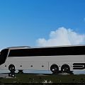 White Bus Parked in Natural Setting With Grass Flowers Water and Blue Sky