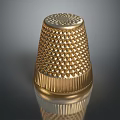 Golden Metallic Thimble Sculpture With Intricate Diamond Patterns And Base Stripes On Reflective Surface