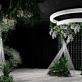 Banquet Hall With Green Plants White Flowers White Circular Decor Silver Stands And Black Backdrop