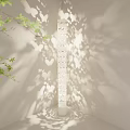 White Floor Lamp With Hollow Out Pattern Casting Shadow Near Green Plant And Picture Frame