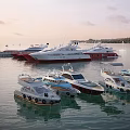 Multiple Luxury Yachts Moored On Calm Water With Larger Vessels And Cloudy Sky Background
