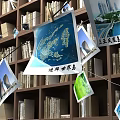 Wooden Bookshelf With Books And Hanging Photos Of World Map And Architectural Views