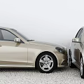Two Beige And Silver Sedans Parked Front Facing Each Other On Pebble Ground