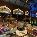 Indian Restaurant With Outdoor Seating Wooden Decor Arched Windows Colorful Tablecloths And Palm Trees
