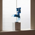 Blue Spiral Metal Sculpture With Gray Square Base Against White Window Blinds Indoor