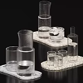 Transparent Glass Cups In Various Shapes Placed On Textured Trays With Water Inside