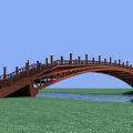 Wooden Arch Bridge Over Water With Railings And Lamp Posts Surrounded By Green Grass