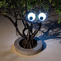 Artistic Tree Light Box Installation With Round Base And Green Foliage