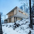 Modern Detached Villa With Curved Roof On Snowy Hillside And Illuminated Windows