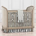 Classic Beige Upholstered Baby Crib With Bow Ties Soft Blanket And Ruffled Skirt