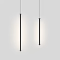 Two Black Elongated Pendant Lights Hanging In Gray Interior With Soft Lighting