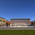 Multi Story Red Brick School Building With Front Plaza Green Lawn And Palm Trees