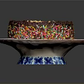 Chocolate Cake With Golden Cream Topping And Colorful Sprinkles On Blue And White Plate