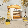 Dessert Shop with Giant Donut Sign Outdoor Yellow Tables Chairs and Trees Around White Kiosk