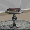 Black Round Top Side Table With Decorative Base And Books On Top On Round Rug