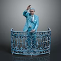 Man in blue suit waving hand behind blue iron railing with intricate floral design