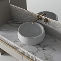 Modern White Round Washbasin With Golden Faucet On Marble Countertop And Textured Wall