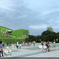 Green Modern Two Story Container Building With Outdoor Cafe Seating And People