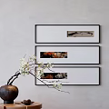 Three Framed Artworks on Gray Wall with Vase and White Flowers on Small Table