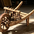 Ancient Wooden Wheelbarrow With Rustic Design And Large Spoked Wheel Structure