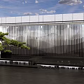 Modern Metallic Feature Wall With Vertical Stripes Green Pine And Water Feature Under Blue Sky