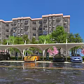 Outdoor Parking Canopy with Cars Parked Under Green Trees and Pink Flowers Near Residential Building