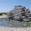 Outdoor Garden Rock Waterfall Feature With Pond Water Lilies And Green Hedges