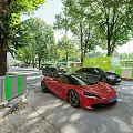 Red Sports Car Parked On Street With Green Fence And Trees
