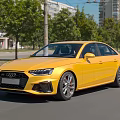 Yellow Audi Sedan Driving On City Street With Trees And Buildings