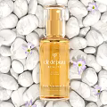 Clé de Peau Beauté Body Treatment Oil with White Pebbles and Purple Flowers