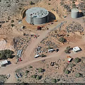 Desert Industrial Facility Aerial View With Two Large Cylindrical Tanks Vehicles Small Buildings and Vegetation