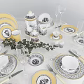 Elegant Tableware Set Featuring Yellow White Plates Cups Teapot Champagne Flutes And Green Leaves