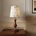 Elegant Table Lamp with Wooden Base Gold Accents and Floral Patterned Lampshade by Beige Chair