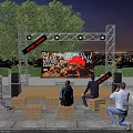 Outdoor Stage Scene With Bright Lights People On Wooden Crate Seats And City Night View