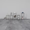 Black Metal Frame Plant Stands Displaying Various Vases and Flowers Against Gray Wall and Floor
