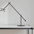 Modern Black Table Lamp With Adjustable Arm On White Desk And Light Background
