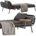 Comfortable Gray Ottoman With Woven Backrest Cushions Wooden Small Round Table And Draped Blanket
