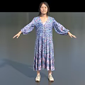 Woman In Blue Purple Floral Long Sleeve Dress Standing With Arms Outstretched On Gray Background