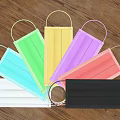Various Colored Disposable Face Masks With Ear Loops On Wooden Background