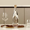 Elegant Transparent Wine Bottle with Gold Cap and Glasses on Gold Tray Over Light Countertop with Wall Panels