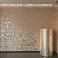 Shiny Metallic Cylindrical Component Next To Gold Textured Wall Surface Design