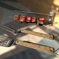 Grill Tools And Skewered Kebab With Fresh Herbs On Tiled Surface