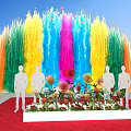Colorful Fountain Launch Device With Flower Display And People Silhouettes Under Blue Sky