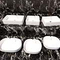 Three Elegant Modern White Washbasins on Black Marble Bathroom Countertop