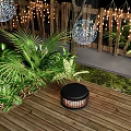 Decorative Outdoor Lights Hanging Over Wooden Deck With Green Plants and Palm Leaves