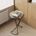 Round Side Table with Glass Top Metal Frame and Stack of Books Near Window