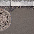 Urban Road Facilities Circular Manhole Cover on Asphalt Surface with Cobblestone Pavement and Curb